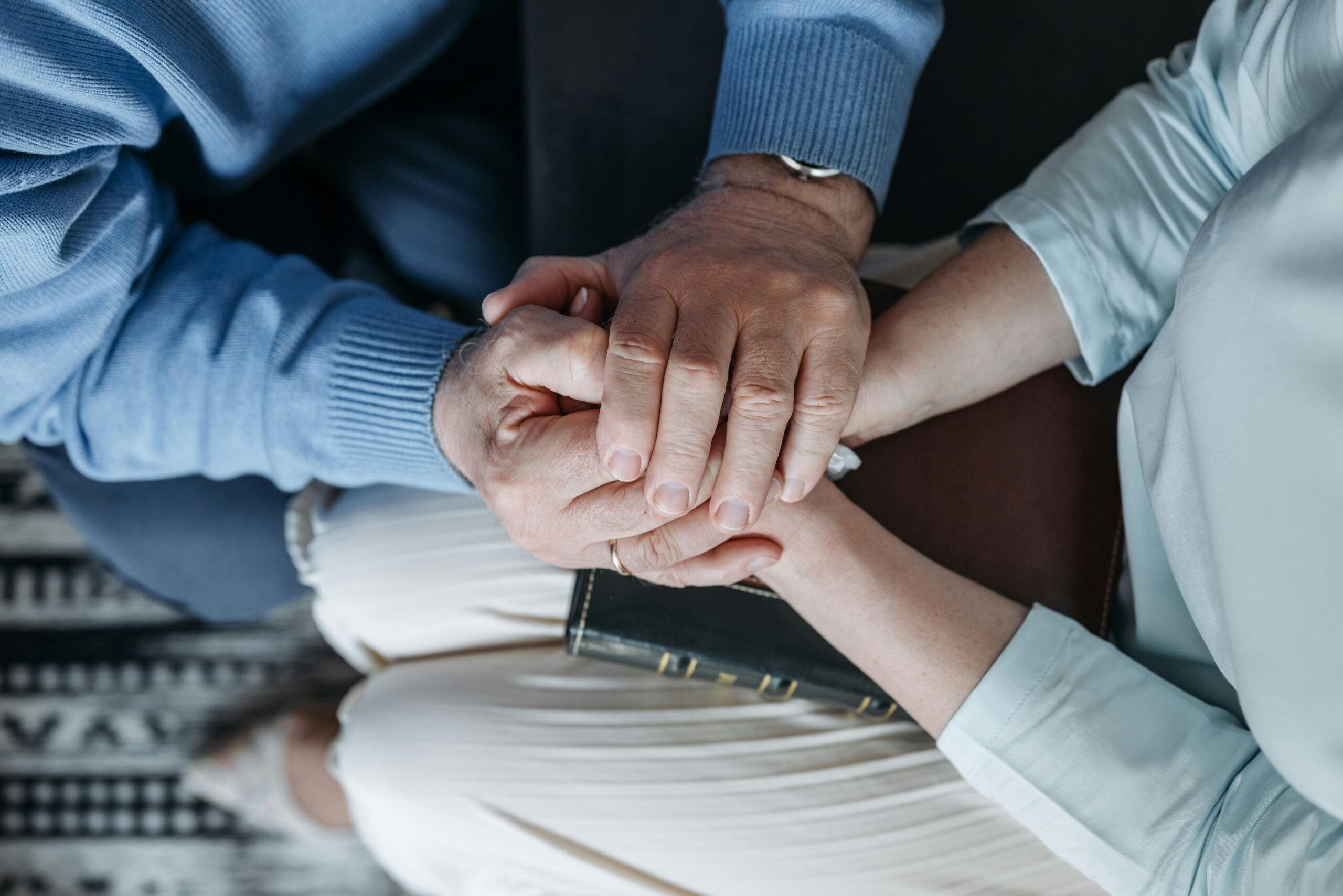Close-up of two people holding hands, expressing comfort and empathy.